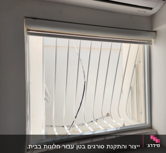 חלון עם סורגים לבנים ותריס גלילה